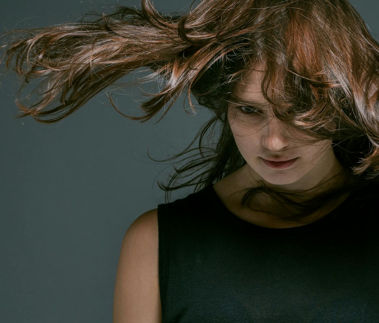 ours-journey Close-up portrait of a woman in motion with hair flying, conveying dynamic energy.